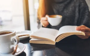 Woman with coffee and reading a book, practicing self-care
